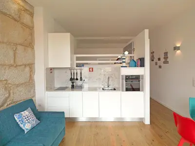 a kitchen with white cabinets and a blue couch at FLH Porto Cozy Studio in Porto