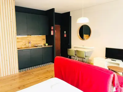 a living room with a red couch and a kitchen at Bolhão Studio in Porto