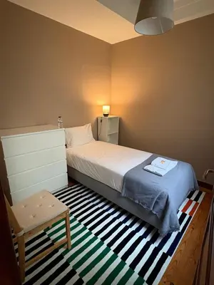 a small bedroom with a bed and a table at Garça Real Flats in Porto