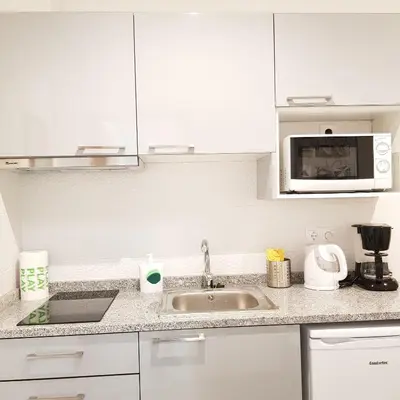 a white kitchen with a sink and a microwave at À Francos Metro in Porto