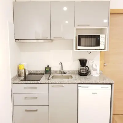 a white kitchen with a sink and a microwave at À Francos Metro in Porto