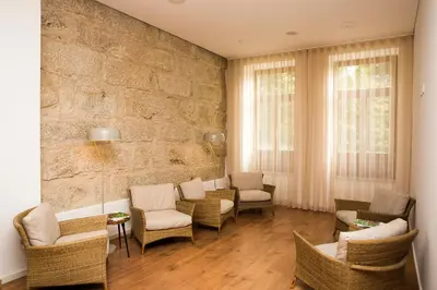 a living room with chairs and a stone wall at BO - Álvares Cabral GuestHouse in Porto