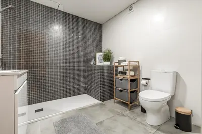 a bathroom with a toilet and a shower with black tiles at FT'Studio in Porto