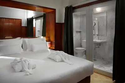 a bedroom with a large white bed and a bathroom at Casa Rosa in Porto