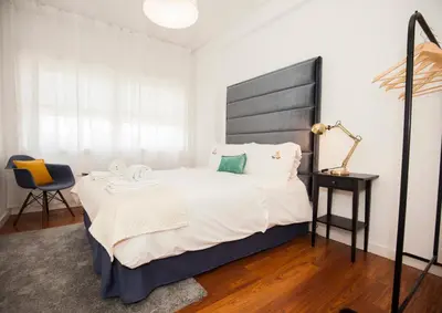 a bedroom with a large bed and a chair at ML Apartments Charming Rooms in Porto