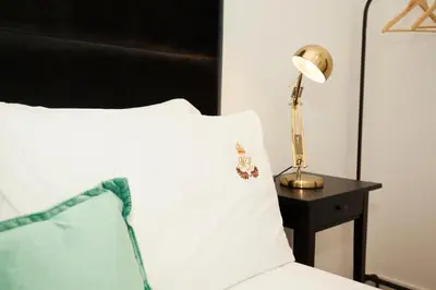 a bed with a white pillow and a lamp on a table at ML Apartments Charming Rooms in Porto
