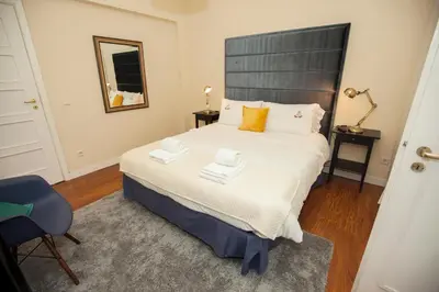 a bedroom with a large bed and a blue chair at ML Apartments Charming Rooms in Porto