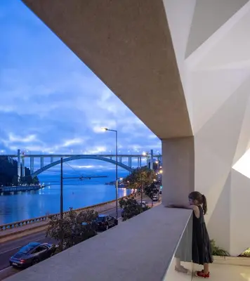 a woman standing on a balcony with a view of a bridge at LeBlanche in Porto