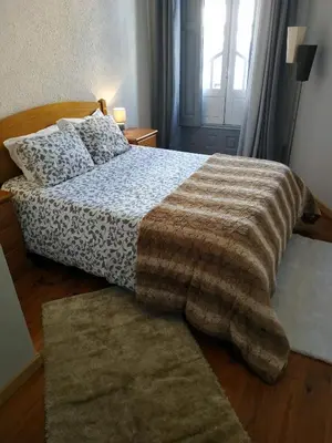 a bedroom with a bed with a blanket and a rug at Gabriel Guesthouse in Porto