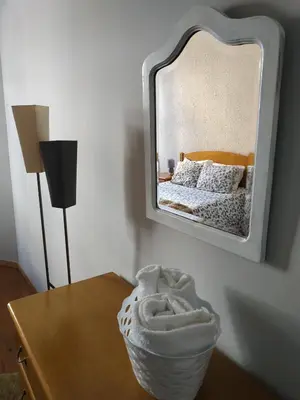 a mirror on a wall above a table with a bed at Gabriel Guesthouse in Porto