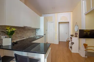 a kitchen with white cabinets and a black counter top at São Domingos Flowers Apartments in Porto