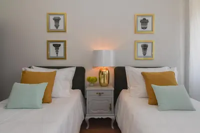 two beds with white and orange pillows in a room at Rosario's Boutique Apartments in Porto