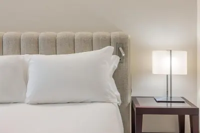 a bed with a white pillow and a table with a lamp at Crowne Plaza Porto by IHG in Porto