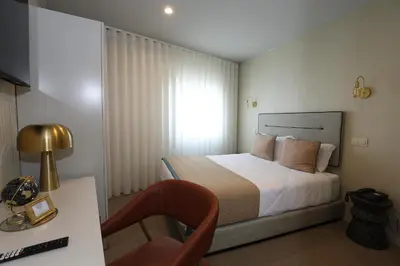 a bedroom with a bed and a chair and a window at Hotel America in Porto