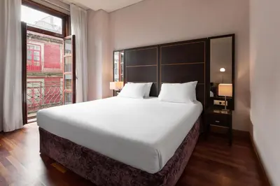 a large white bed in a room with a window at Eurostars das Artes in Porto