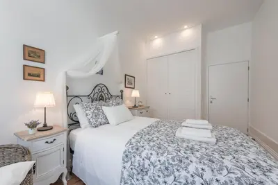 a bedroom with a white bed with a blue and white blanket at GuestReady - Feels like Heaven in Porto