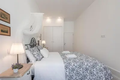 a bedroom with a large white bed with a floral bedspread at GuestReady - Feels like Heaven in Porto