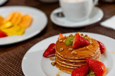 a stack of pancakes with strawberries and nuts on a table at HF Ipanema Porto in Porto