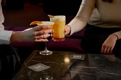 two people are holding drinks on a table at HF Ipanema Porto in Porto