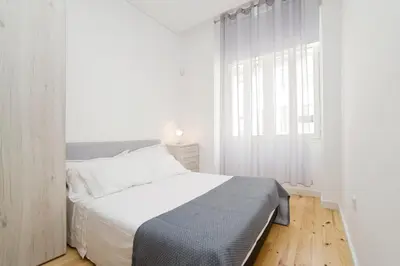 a white bedroom with a bed and a window at Oporto Cool - Fontainhas in Porto