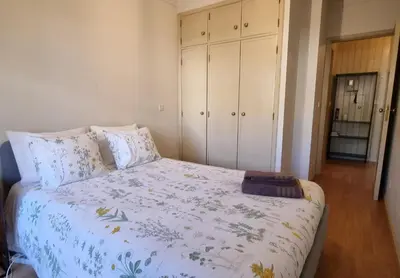 a bedroom with a bed with a floral bedspread and white cabinets at Cozy Apartment Casa da Música in Porto
