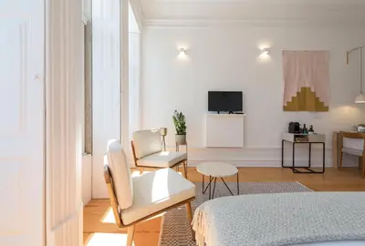 a white room with a bed and two chairs at Tripas-Coração, São Bento Apartments in Porto