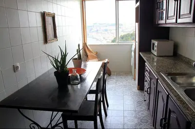 a kitchen with a table with chairs and a window at Historical Porto/Gaia Apartment in Porto