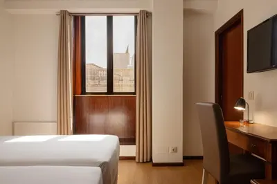 a bedroom with a bed and a desk and a window at Hotel da Bolsa in Porto