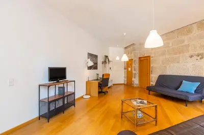 a living room with leather furniture and a stone wall at Casa Trindade Apartments in Porto