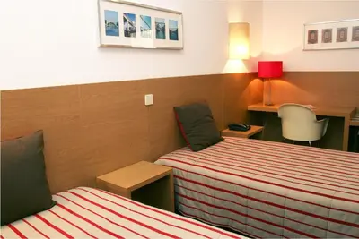 a hotel room with two beds and a desk at Costa do Sol B&B in Porto