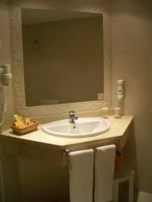 a bathroom with a sink and a mirror and towels at Costa do Sol B&B in Porto