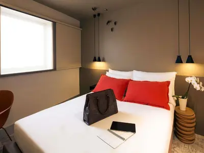 two glasses of wine and a bowl of fruit on a bed at Mercure Porto Centro Santa Catarina in Porto