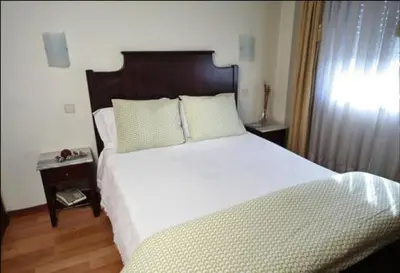 a bedroom with a large white bed with a wooden headboard at Hotel Palanca in Porto