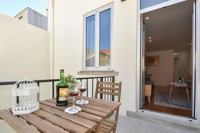 a wooden table with wine glasses and a bird cage on a balcony at Oporto Lovely House in Porto