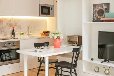 a kitchen with a table with two chairs and a tv at Indulge Porto Flats in Porto