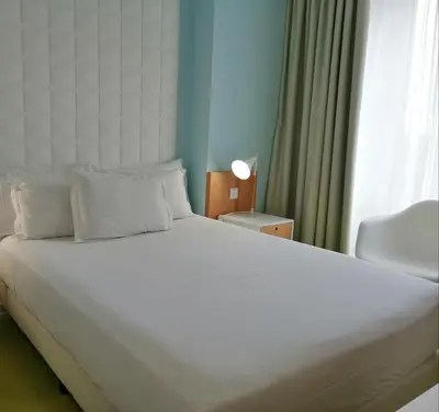 a large white bed in a room with a window at Legendary Porto Hotel in Porto
