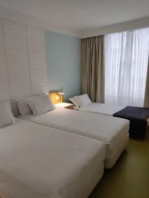 two white beds in a hotel room with a window at Legendary Porto Hotel in Porto