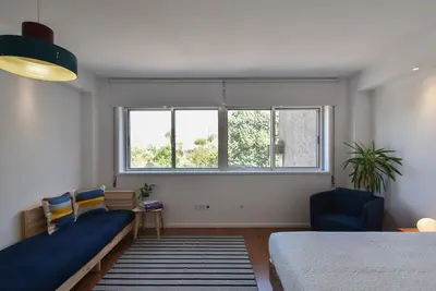 a bedroom with a bed and a large window at Porto Republica Flat in Porto