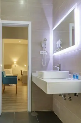 a bathroom with a sink and a living room at Porto Domus Hotel in Porto