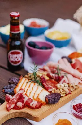 a wooden table topped with meats and a bottle of beer at Boavista Guest House in Porto