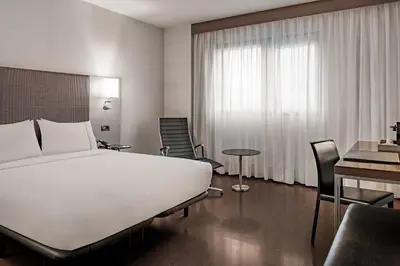 a hotel room with a white bed and a table and chairs at AC Hotel Porto by Marriott in Porto