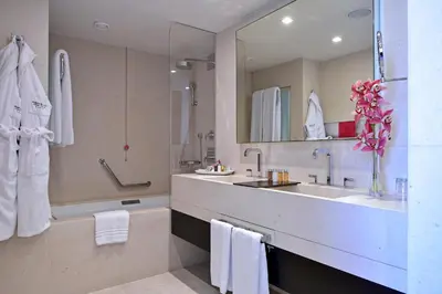 a bathroom with two sinks and a tub and a mirror at Porto Palácio Hotel by The Editory in Porto