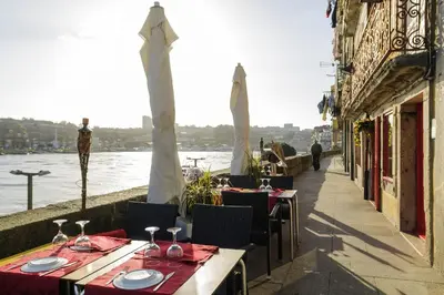 a restaurant with tables and chairs next to the water at YOUROPO - Ribeira Porto in Porto
