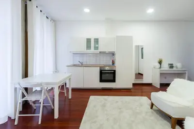 a living room with a table and a kitchen at Flores Studio in Porto