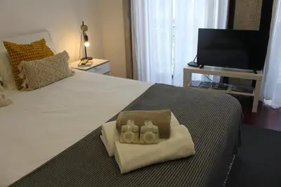 a bedroom with a bed with two towels and a television at Flores Central in Porto