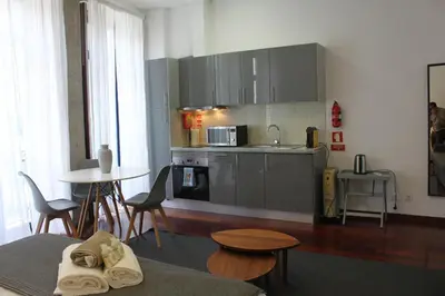 a kitchen with stainless steel appliances and a table and chairs at Flores Central in Porto