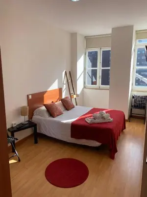 a bedroom with a bed with a red blanket and two windows at Formosa Oporto Apartments Group in Porto