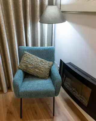 a blue chair with a pillow sitting next to a fireplace at Bruval Premium Apartments - Sé Porto in Porto
