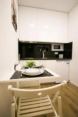 a kitchen with white cabinets and a table with a chair at Bruval Premium Apartments - Sé Porto in Porto