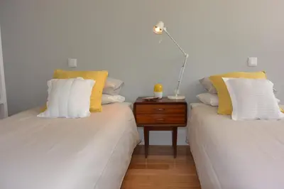 two beds with yellow and white pillows and a night stand at Casa Paillard, by Flat in Porto in Porto